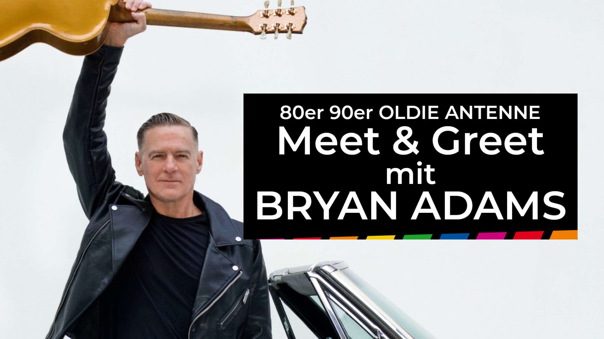 Bryan Adams mit einer Gitarre in der Hand, die er in die Luft streckt